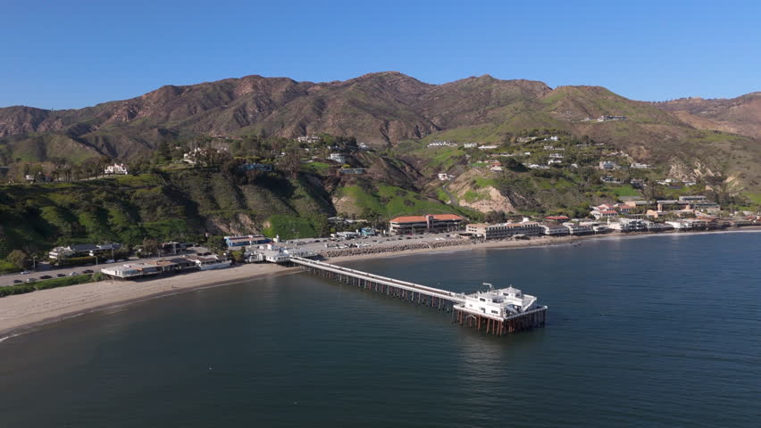 Explore stunning aerial drone shots of Malibu Pier, California. Enjoy scenic ocean views and lush hills in this coastal paradise, ideal for relaxation, exploration, and outdoor fun