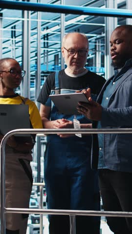 Vertical video Smart factory team leader and colleagues implement automated workflows and control systems, computerizing manual operations. Coworkers integrate sensors into conveyor belts, camera A