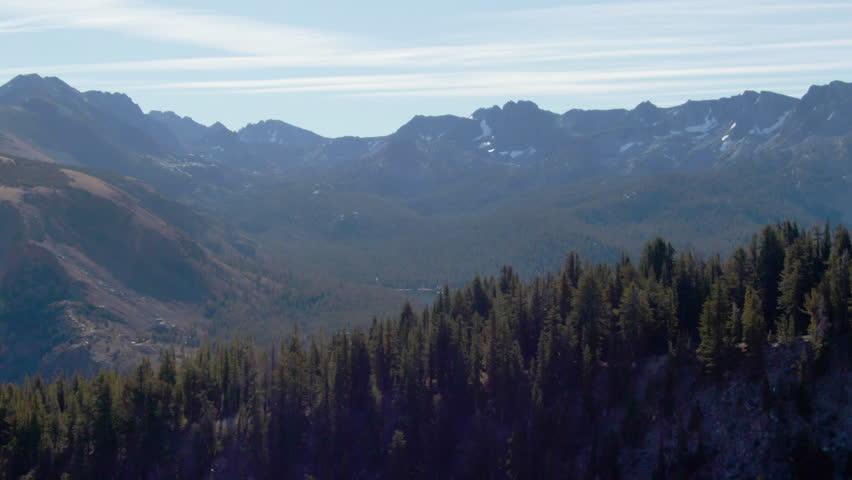 An aerial footage of a forest on mountain, revealing Twin Lakes and the surrounding mountains located in Mammoth Lakes, California, USA on a sunny day