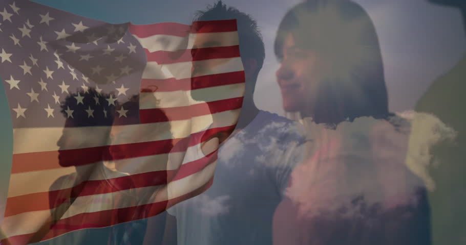 American flag waving, people standing under cloudy sky, feeling patriotic atmosphere. Patriotism, national, unity, pride, freedom, celebration