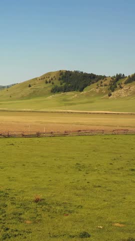 Vertical aerial video of Altai rural landscape. Wooden fence in the foreground. Drone moving along hedge. 
