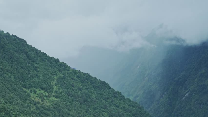Dramatic Valley Landscape in Mountains, Green Mountainous Valley with Trees and Low Lying Clouds in the Himalayas Mountains in Nepal, Amazing Views while Trekking and Hiking in Nepal