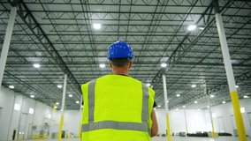 Shot of Inside large commercial warehouse that person in yellow work jacket who walks - Powered by Shutterstock - Get 15% off with code: PIKWIZARD15