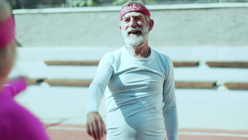 An active senior gentleman enjoys sports activities with enthusiasm, surrounded by friends