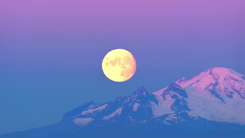 A captivating time-lapse video capturing the serene beauty of a full moon rising over a majestic mountain range. 