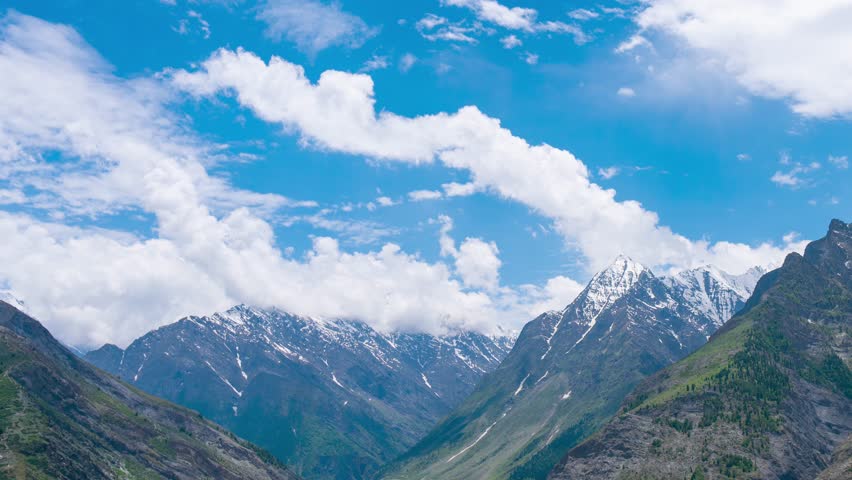 4K timelapse of white fluffy clouds moving in blue sky over Himalaya mountains in Lahaul, India. Himalayan Mountains during the sunny summer day. Timelapse of clouds on mountains