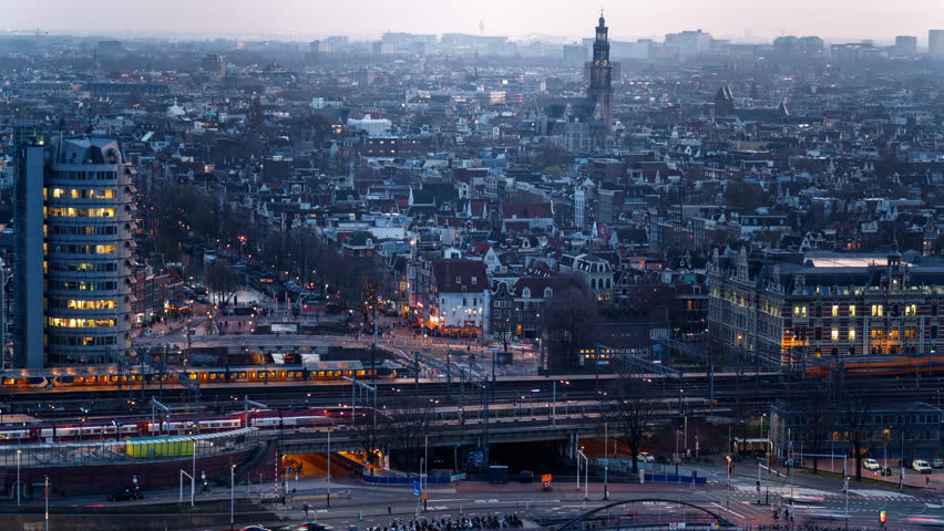 Amsterdam cityscape at night with illuminated streets, moving trains, and historical architecture. A vibrant urban skyline blending modern transit with classic Dutch charm. Timelapse shot.