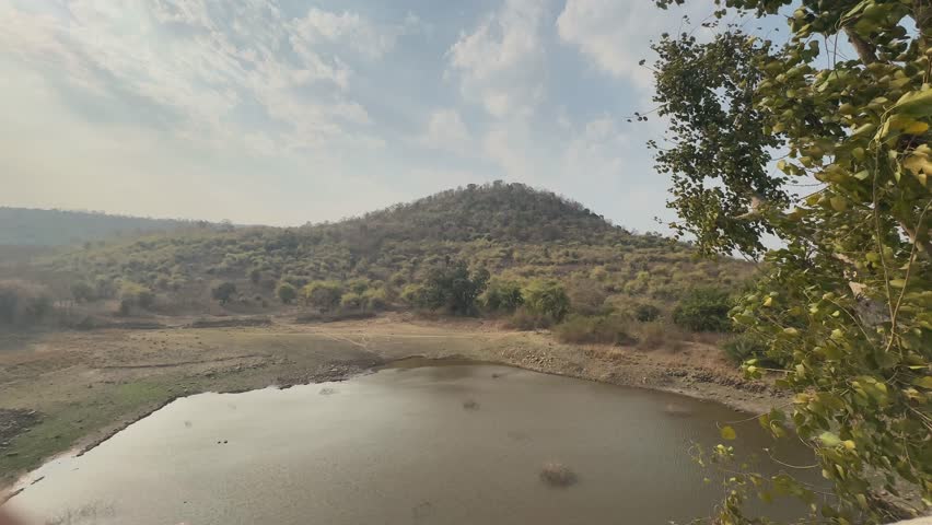wide angle shot of lake near mountain with pluffy blue cloud