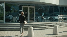 Businesswoman walking towards modern glass office building holding handbag, with sleek reflections of parked cars on facade, showcasing professional lifestyle in urban setting - Powered by Shutterstock - Get 15% off with code: PIKWIZARD15