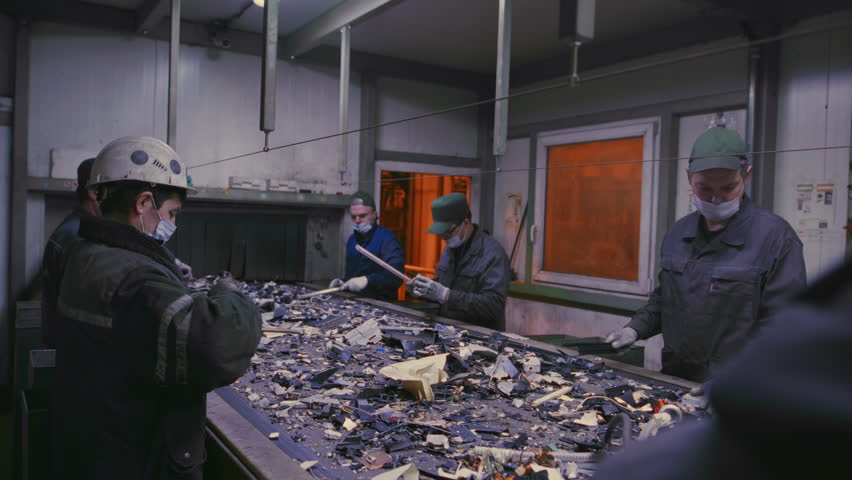 Trash sorting. Conveyor for waste. Recycling garbage. Men sort metal garbage on a conveyor. Recycle process, secondary use of plastic. Recycling factory. Male workers recycle scrap metal. Littering