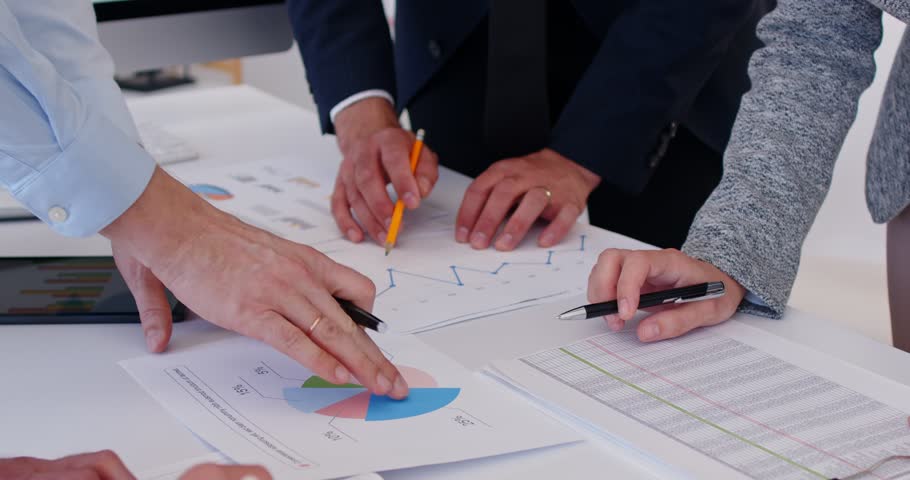 A project management meeting and discussing timelines and deliverables, analysing together on company growth goals and gross profit margins investment reports to clients at office table.