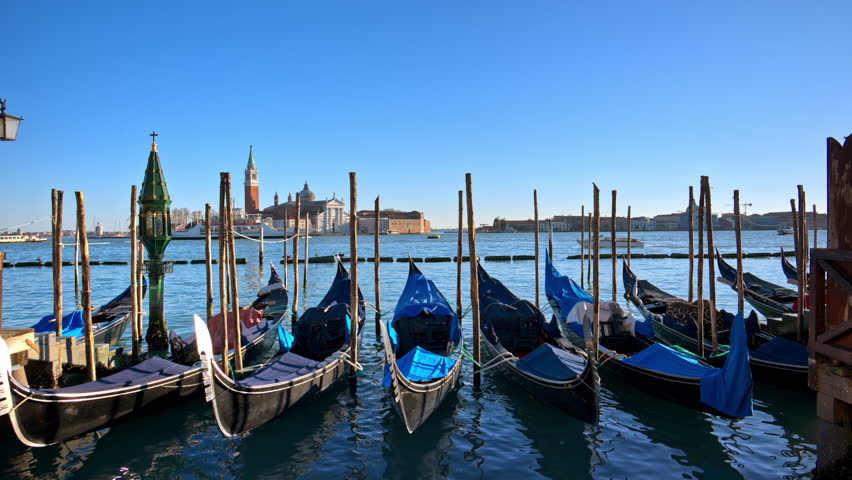 Multiple gondola boats docked on the side of a canal in Venice City, Italy