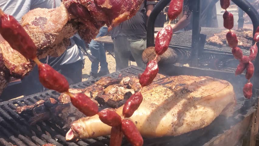 Outdoor cooking scene. Grilled meat and sausages on barbecue grill. Man cutting pieces of meat background