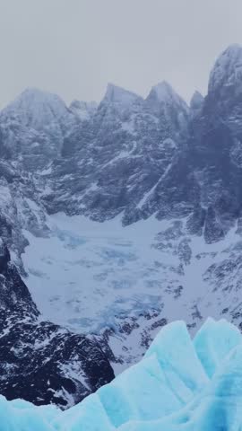 A vertical closeup footage of the Grey Glacier featuring snow-covered mountain with mist at Torres del Paine National Park in Magallanes, Chile