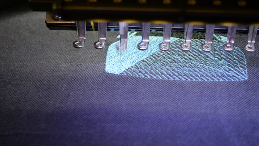 Machine embroidery of a sports car with blue and black thread on a t-shirt. Embroidery of clothes for a gift. Car embroidery design. 4k 5fps video close-up.