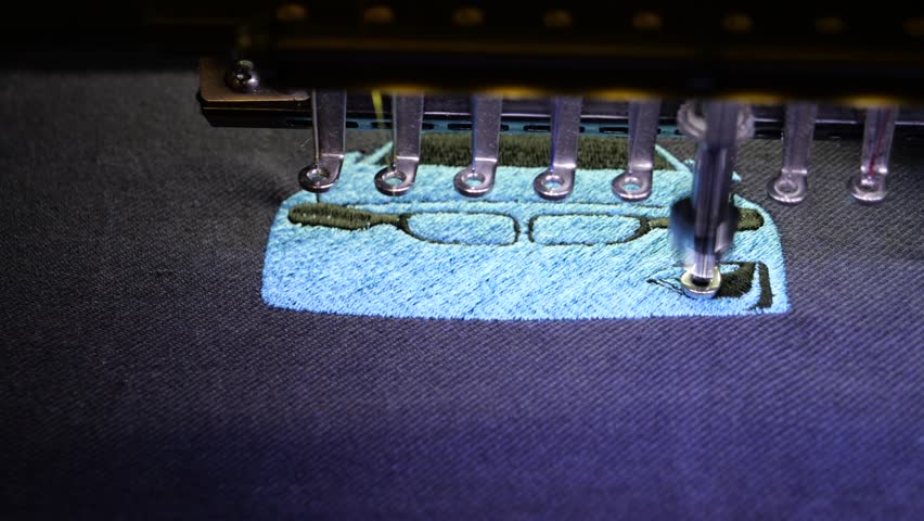 Machine embroidery of a sports car with blue and black thread on a t-shirt. Embroidery of clothes for a gift. Car embroidery design. 4k 5fps video close-up.