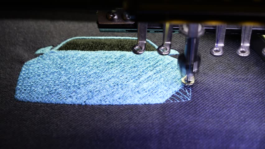 Machine embroidery of a sports car with blue and black thread on a t-shirt. Embroidery of clothes for a gift. Car embroidery design. 4k 5fps video close-up.