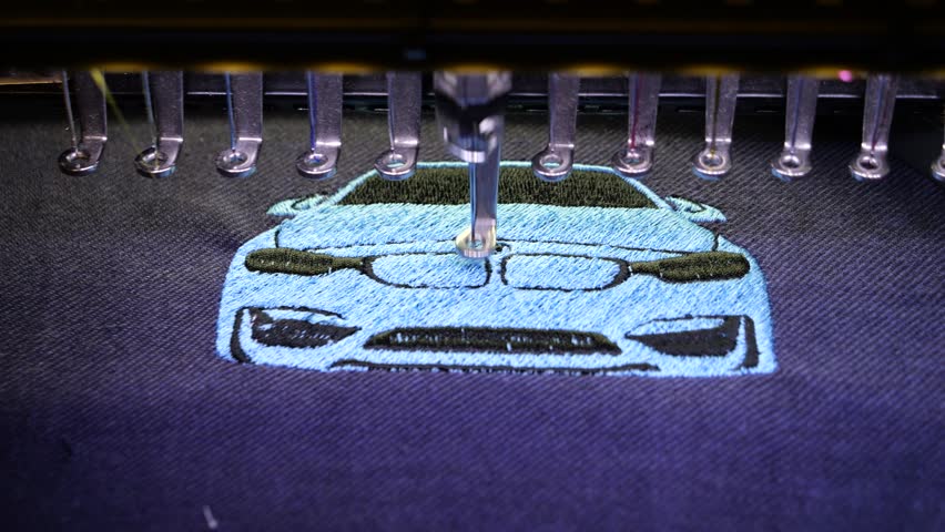 Machine embroidery of a sports car with blue and black thread on a t-shirt. Embroidery of clothes for a gift. Car embroidery design. 4k 5fps video close-up.