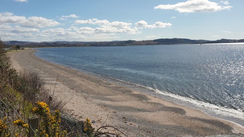Scenic view of beautiful long curved beach and ocean water in Argyll region of Scotland UK