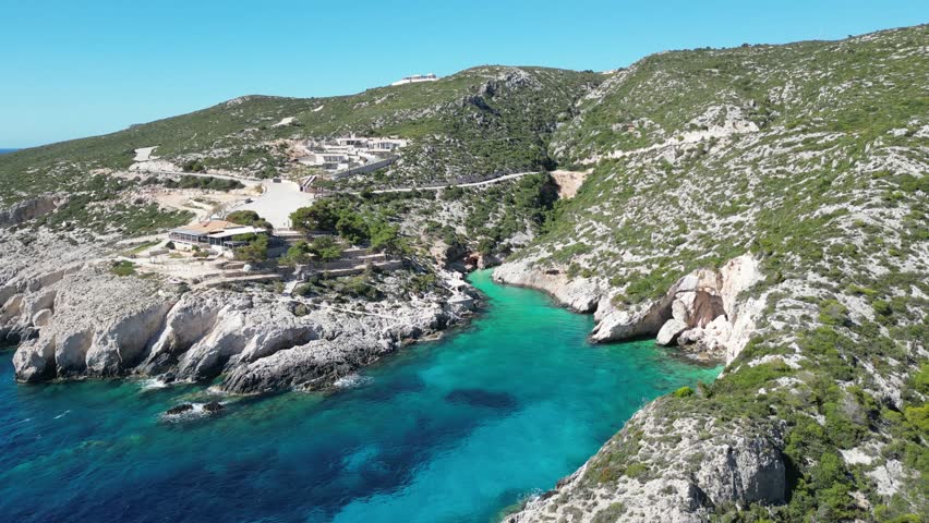 An aerial view of crystal-clear waters with rocky beach under clear sky in Agios Leon, Zakynthos Island, Greece
