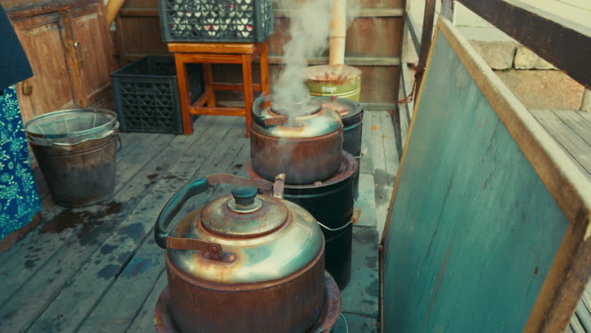 A person is seen tending to large steaming kettles in a rustic setting in Wuzhen, China.