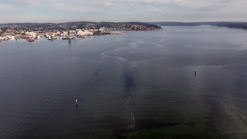 flying from Port Orchard across Sinclair Inlet toward  Bremerton Ferry Terminal and Marina with many boats moored and Puget Sound Naval Shipyard to the left - 4k aerial video footage