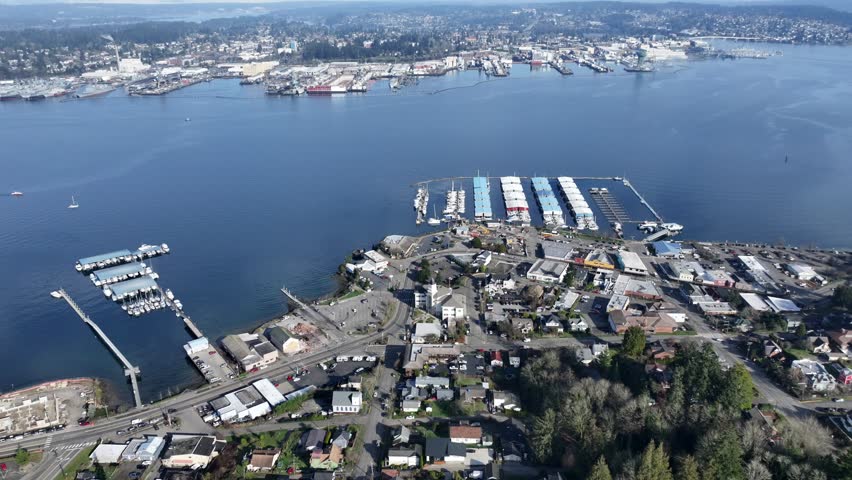 4k aerial video footage, hovering near Port Orchard Marina with boats moored at piers, located at Sinclair Inlet with Bremerton and Puget Sound Naval Shipyard in background