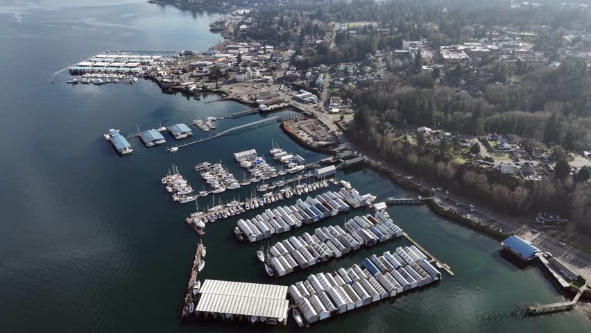 flying above and around  Port Orchard Marina and Port Orchard Foot Ferry Dock, panning left and tilting up while Puget Sound Naval Shipyard and Bremerton becomes visible - 4k video footage