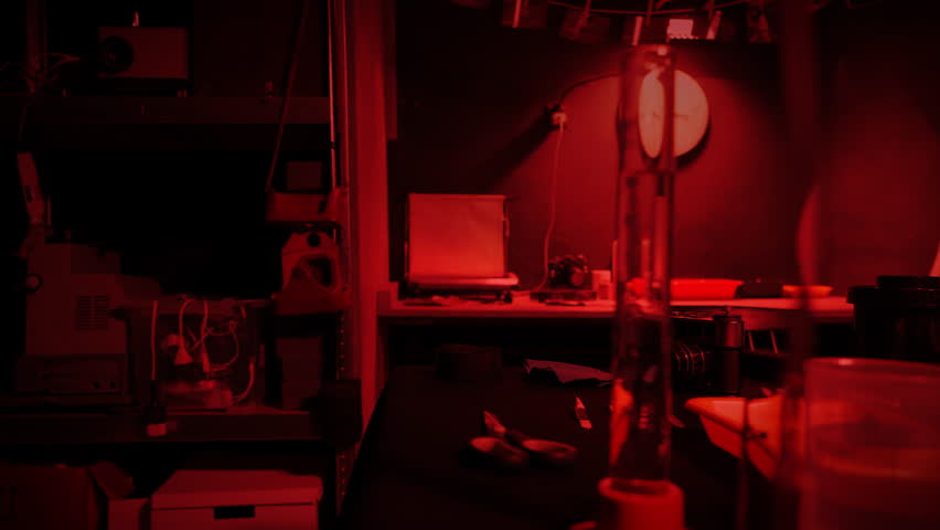 Developing photos in a photography studio. Old school photo film negatives processing. Darkroom with red light. Selective focus