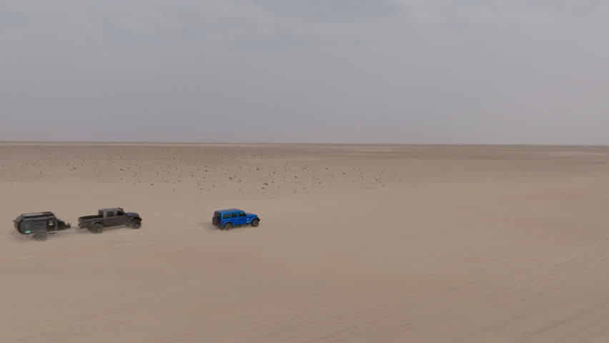 Trucks driving fast through Oman desert on road to Bar Al Hikman, wide open and dry