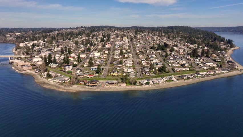 flying from Manette community across Puget Sound to Bremerton Marina with "Manette Bridge" across Port Washington Narrows and mountain landscape in background - 4k aerial video footage