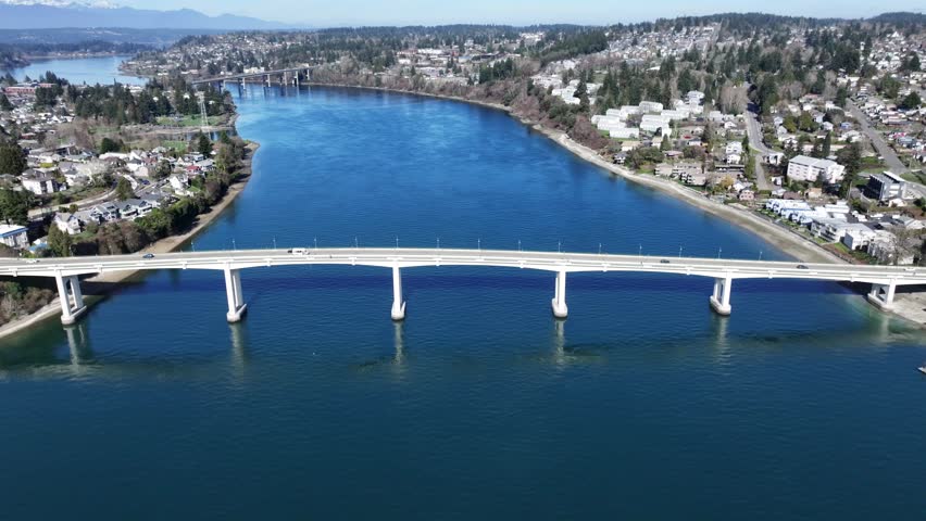 backwards flying from Bremerton "Manette Bridge" across Port Washington Narrows with right panning across community of Manette, "Warren Avenue Bridge" in Background , 4k, aerial video footage