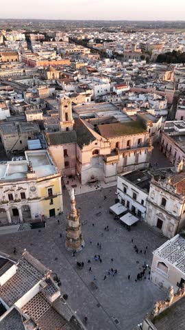Aerial drone view of Nardo, a historic town in southern Italy, bathed in golden sunset light. The old towns dense architecture, whitewashed buildings, and narrow streets highlight its rich cultural