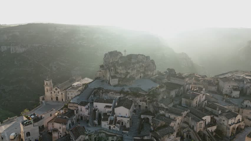 Aerial drone view of Basilica Cattedrale di Matera and the surrounding ancient stone dwellings in Matera, Italy. The historic landscape, carved into the rugged hills, highlights the city