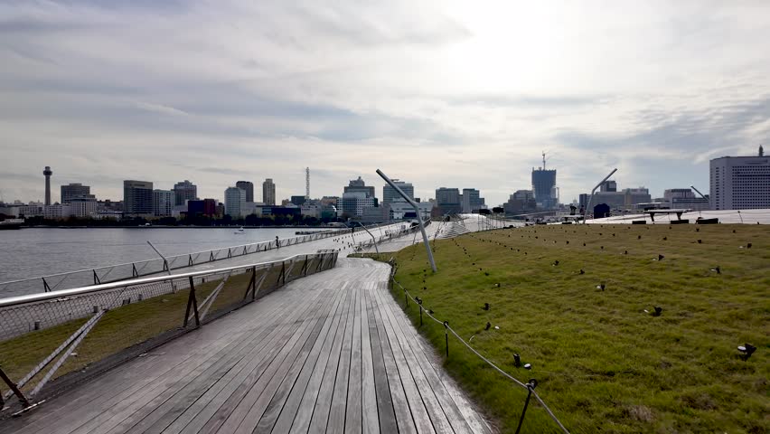 Modern wooden walkway leading to Yokohama skyline on a cloudy day, view from Osanbashi Pier