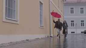 Loving couple running together under vibrant red umbrella, playfully embracing rainy day moment with joyful connection and shared romantic experience - Powered by Shutterstock - Get 15% off with code: PIKWIZARD15