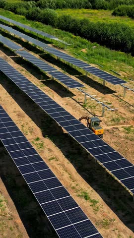 Vertical, aerial: solar panels in a field during the day, outdoor, orbit drone shot