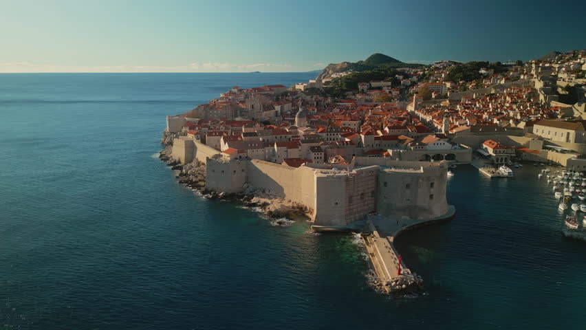 Gorgeous fort Lovrijenac and Dubrovnik town on calm sea coast camera moving around. Travelling to neat medieval city with port protected by fortress in Croatia aerial panorama