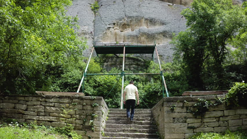 Approaching drone shot of a tourist walking towards a tourist spot of the Madara Rider, Madara Horseman, or more known locally as Madarski Konnik in the Madara Plateau near Shumen in Bulgaria.