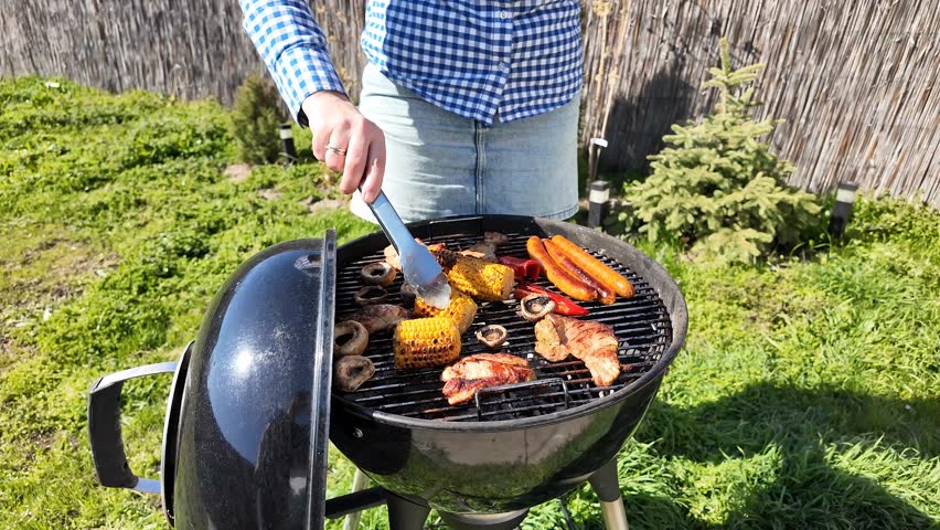 White male grilling assorted vegetables and meats on barbecue, outdoor cooking, summer picnic, Labor Day celebration, backyard gathering