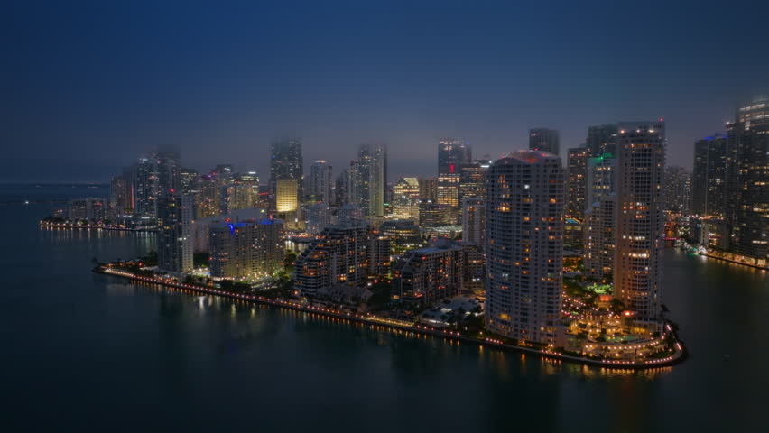 Experience stunning aerial footage of Downtown Miamis vibrant skyline, lively nightlife, and picturesque Brickell Key glistening under a starry night sky, offering a mesmerizing view