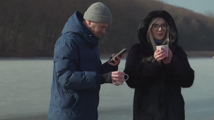 A Couple Delightfully Enjoying Hot Beverages Together in a Beautiful Winter Scenic Setting