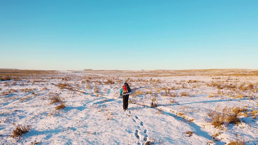 Aerial view of a lonely human walking through snowy desert. Extreme tourism and the concept of survival in extreme cold conditions. FHD footage.