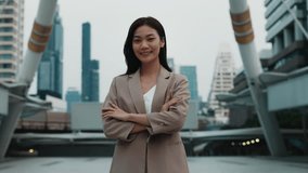 Portrait of young Asian female with confident smile crossing arms standing in megapolis environment. Thai business lady shows determination to reach success. Stylish corporate worker - Powered by Shutterstock - Get 15% off with code: PIKWIZARD15