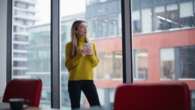 Relaxed lady browsing social media at cellphone in workplace. Calm businesswoman reading message smartphone standing by panoramic window looking city view. Attractive woman watching mobile phone. - Powered by Shutterstock - Get 15% off with code: PIKWIZARD15