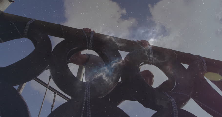 Climbing outdoor structure, man under cloudy sky with stars twinkling in background. Adventure, night sky, exploration, stargazing, silhouette, determination