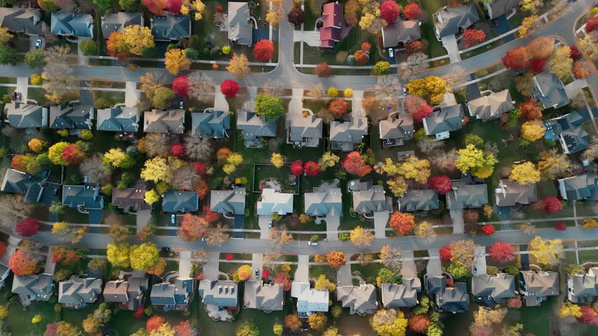 Beaut Scenic suburban surrounded by vibrant red and yellow autumn trees. Warm fall colors create a picturesque seasonal neighborhoods, homes, amid breathtaking Autumn colors, aerial view.