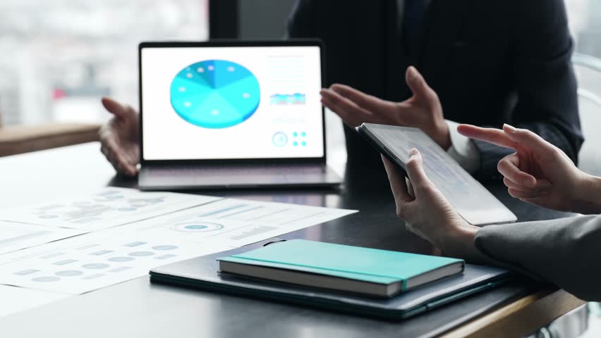 A group of business people having a meeting while looking at the screens of a laptop and tablet PC
