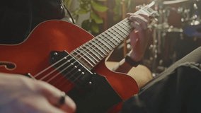 Concentrated guitarist performing melodic riffs on vibrant red electric guitar within professional recording studio, surrounded by comprehensive musical equipment and instruments - Powered by Shutterstock - Get 15% off with code: PIKWIZARD15