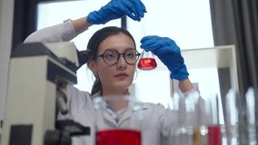 scientist laboratory carefully conducts experiment, holding flask with red liquid while wearing blue gloves and glasses. environment is filled with various lab equipment, showcasing focused - Powered by Shutterstock - Get 15% off with code: PIKWIZARD15